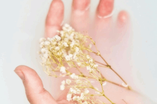 Hand wird in warmen Kräuterbad gelegt um das Gel an den Fingernägeln zu entfernen.