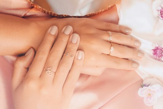 Es sind zwei Frauen- Hände mit schönen Fingernägeln zu sehen. Die Frau trägt zwei Ringe.
