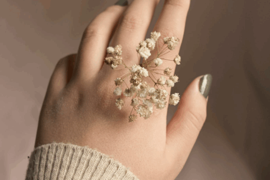 Es ist eine schöne Hand einer Frau zu sehen die dunkelgrünen Nagellack auf den Fingernägeln hat.