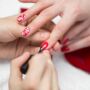 Eine Frau bekommt auf ihre Nägel lackiert und erhält ein individuelles Design in der Farbe Rot und weiß.